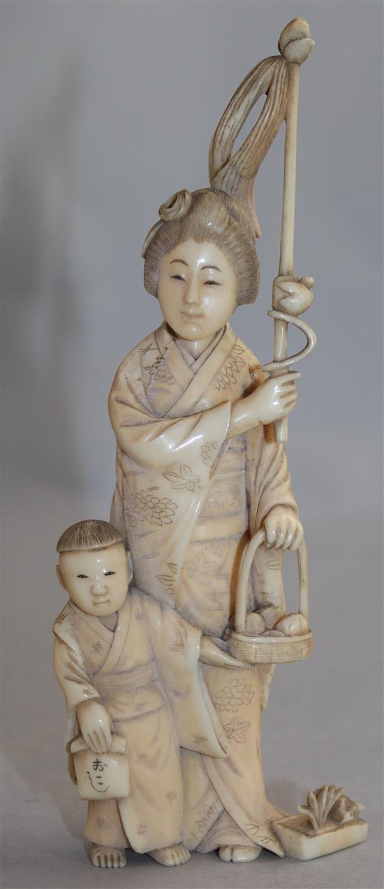 A Japanese ivory group of a woman carrying a basket of pomegranates, Meiji period, 16.8cm